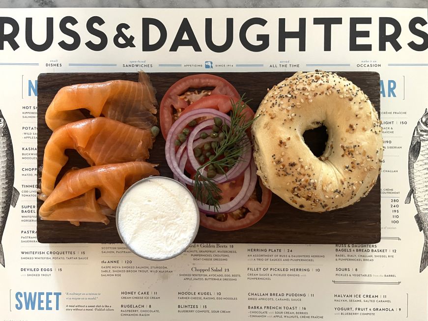 Wooden board with a bagel, lox, and other fixings