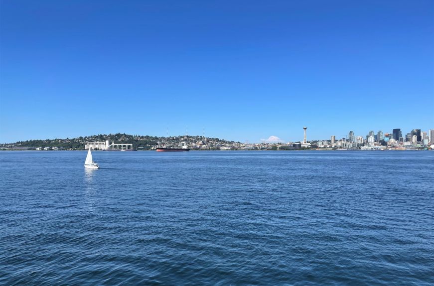 Seattle skyline and Space Needle in the background with water and a sailboat in the foreground