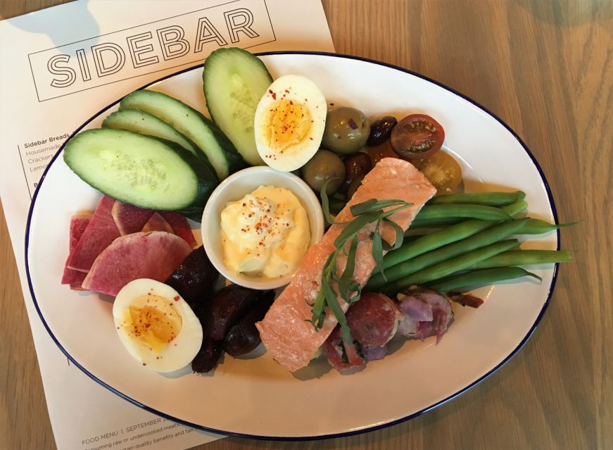 Salmon Nicoise Aioli, Sidebar at Surdyk's Platter with a cup of aioli, vegetables, olives, hard boiled eggs, and a salmon filet