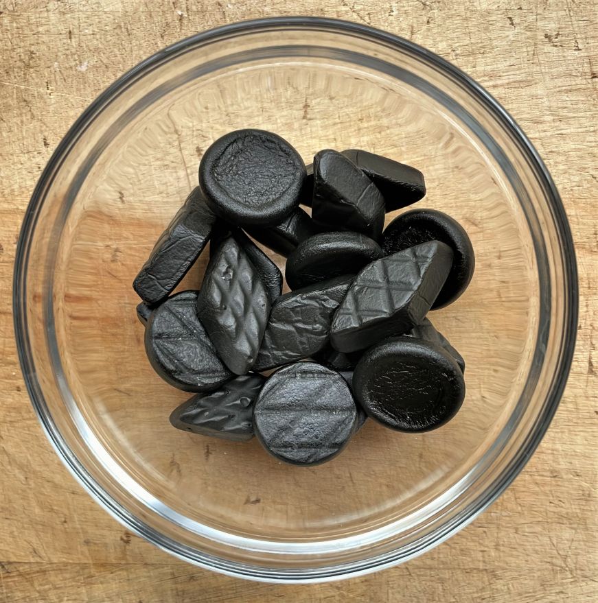 Small glass bowl with round and diamond-shaped pieces of black licorice