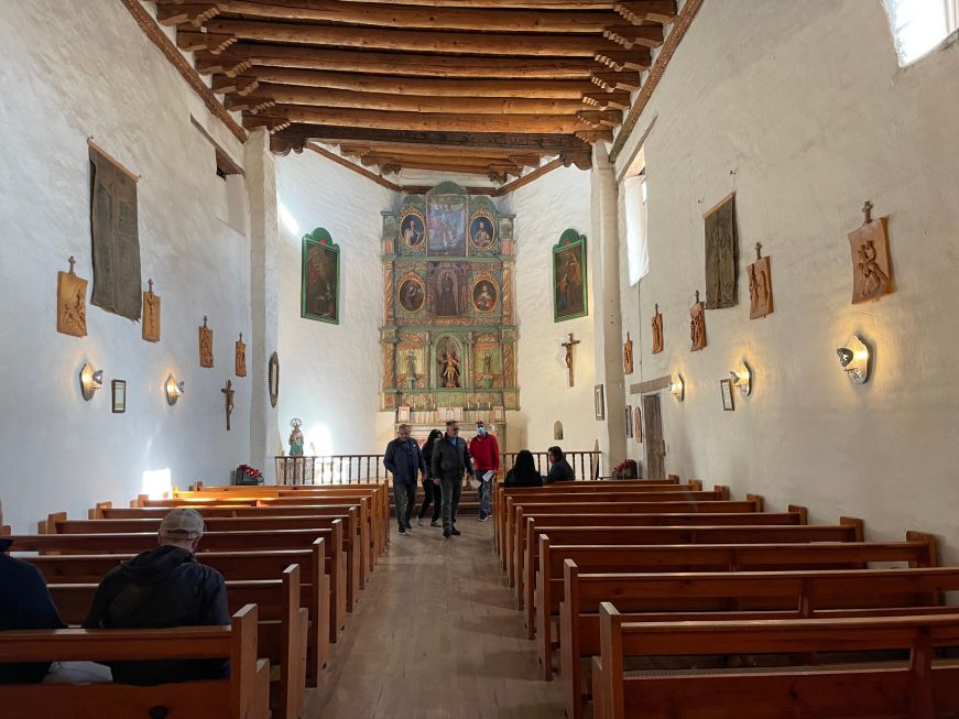 Church interior with white walls, timbered ceiling, and elaborate painted wooden altar