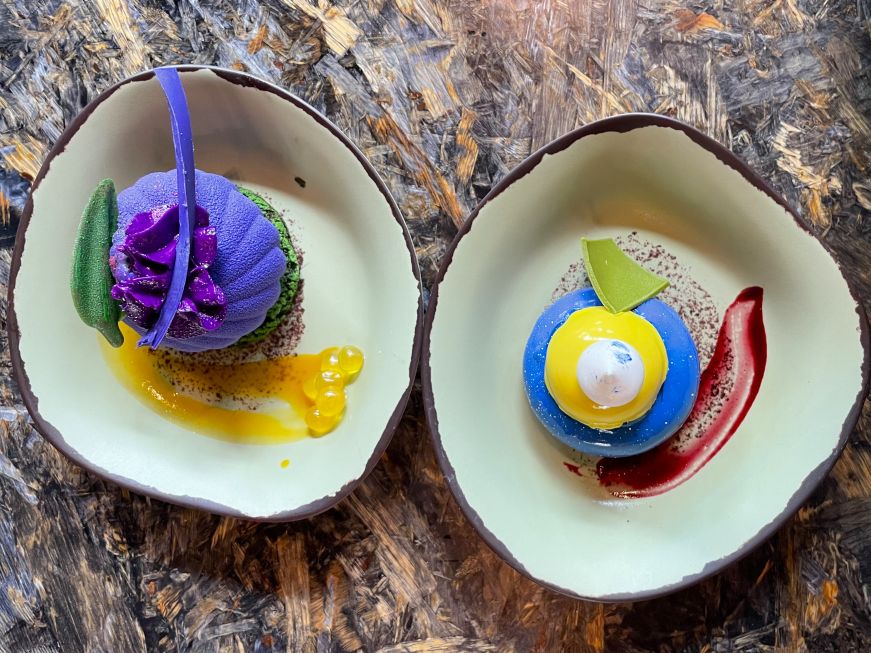 Metkayina mousse and blueberry cream cheese mousse, Satu'li Canteen Top down view of bright purple and bright blue mousse cakes