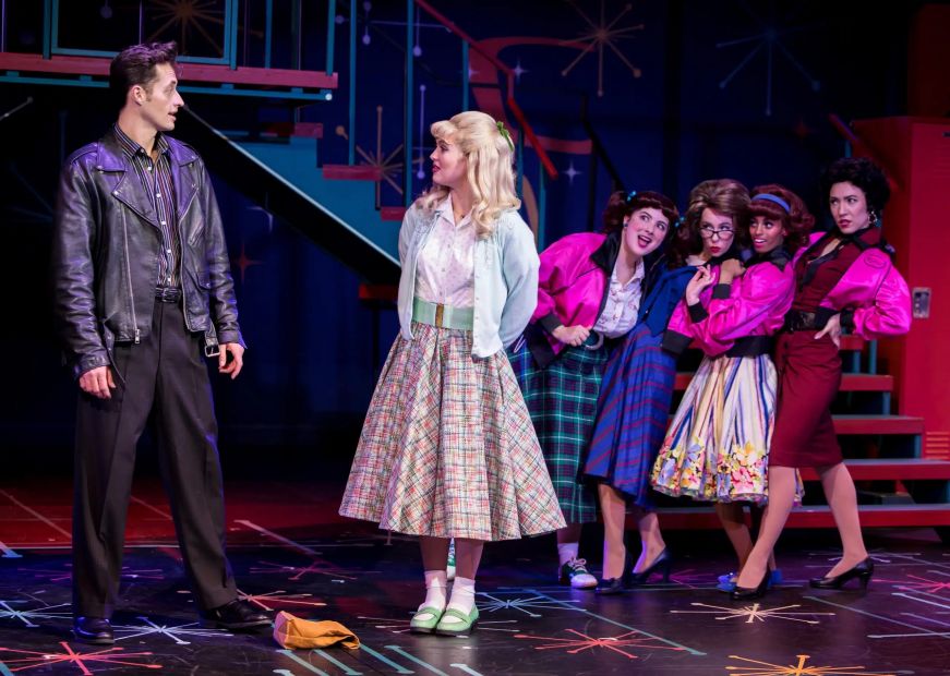 Grease at Chanhassen Dinner Theatres Man wearing a leather jacket and a woman in a full skirt and cardigan on a stage