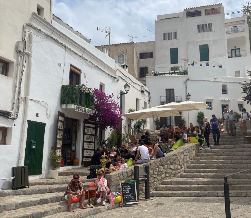 People sitting on stone steps at an outdoor cafe