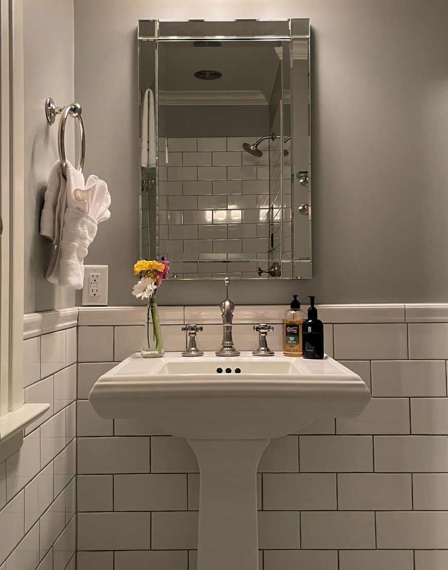 Vintage-style white pedestal sink with a vase of fresh flowers