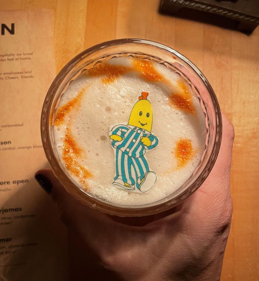 Cocktail garnished with an edible cartoon image of a banana wearing white and blue striped pajamas