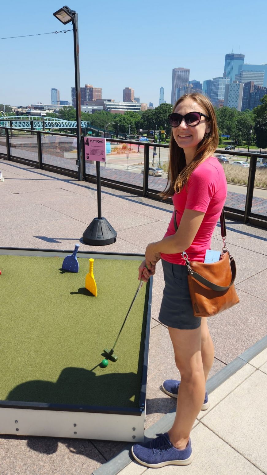 Skyline Mini Golf at the Walker Art Center Stacy playing mini golf on a rooftop with the Minneapolis skyline in the background