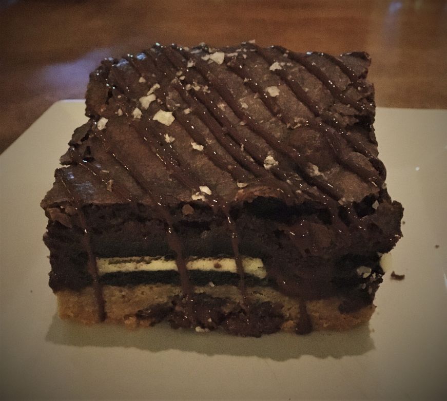 Side view of layered dessert bar with chocolate chip cookie, Oreos, and brownie, Bake'n Babes, Tampa
