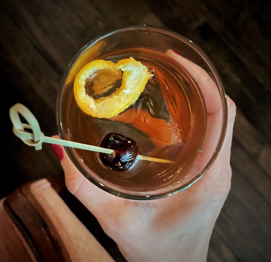 Hand holding old fashioned cocktail