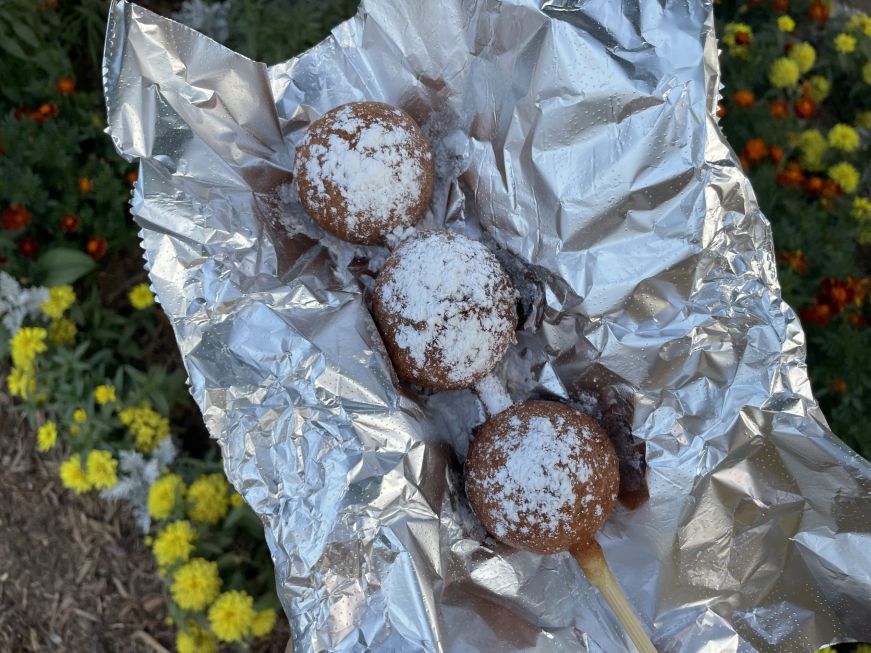 Three spheres of breaded deep-fried cookie dough threaded onto a wooden skewer