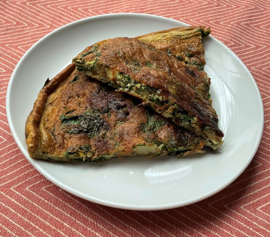 Two slices of Spanish tortilla on a white plate with a red placemat in the background