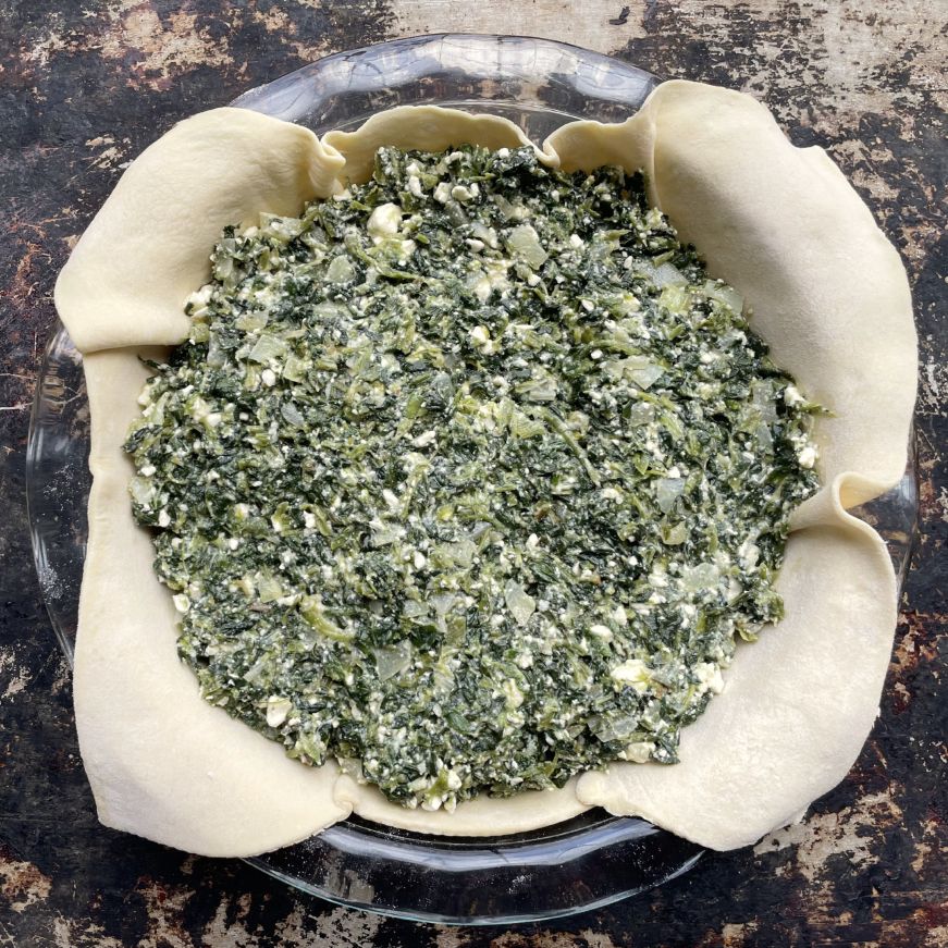 Crust lined pie dish filled with spinach feta mixture