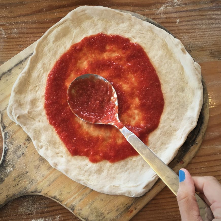 Spreading sauce on pizza with a large spoon, 1889 Pizza Napoletana, Kansas City, Kansas Spreading sauce on pizza with a large spoon, 1889 Pizza Napoletana, Kansas City, Kansas