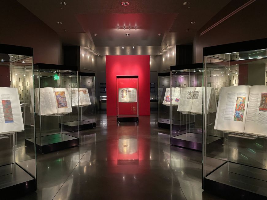 Dim room with illuminated manuscrip pages in display cases 