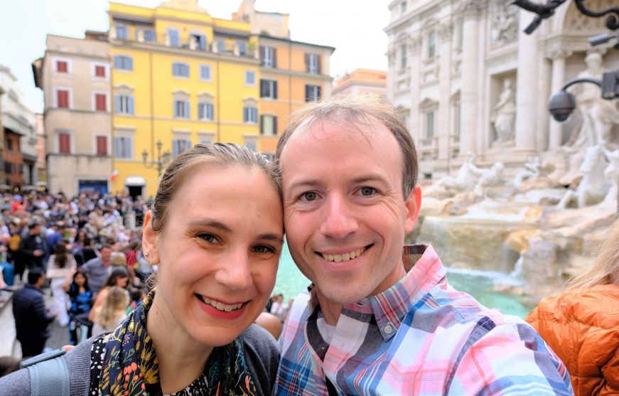 Stacy and Mike with a large crowd and ornate fountain with statues in the background