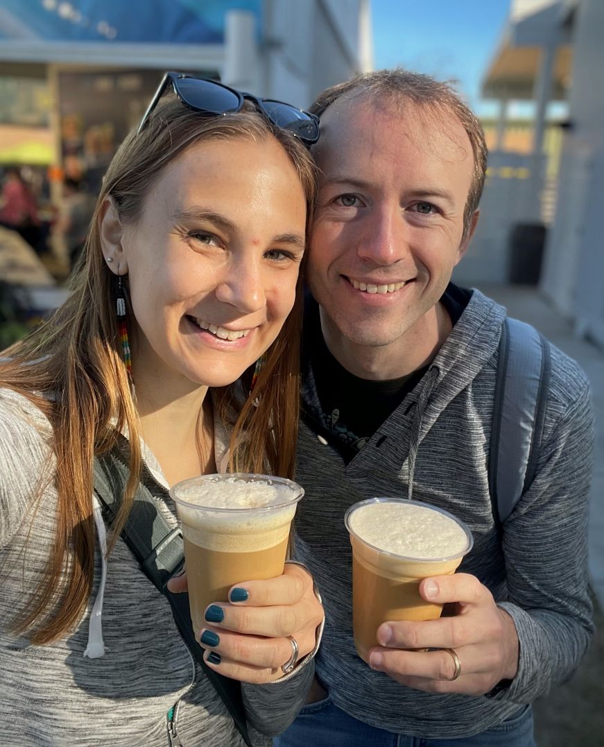 Stacy and Mike wearing hoodies and holding iced coffees