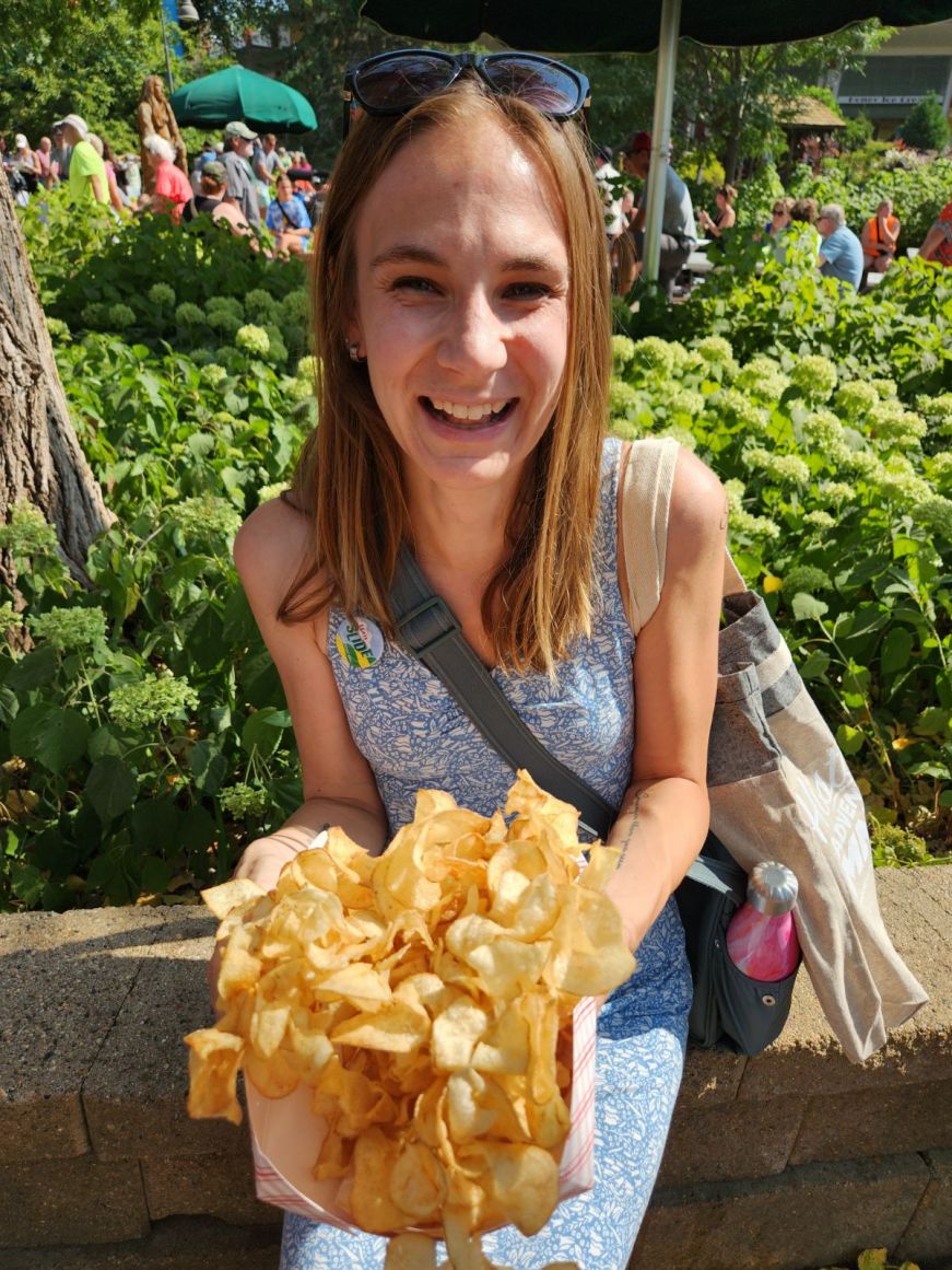 Stacy holding a cardboard dish piled high with potato chips