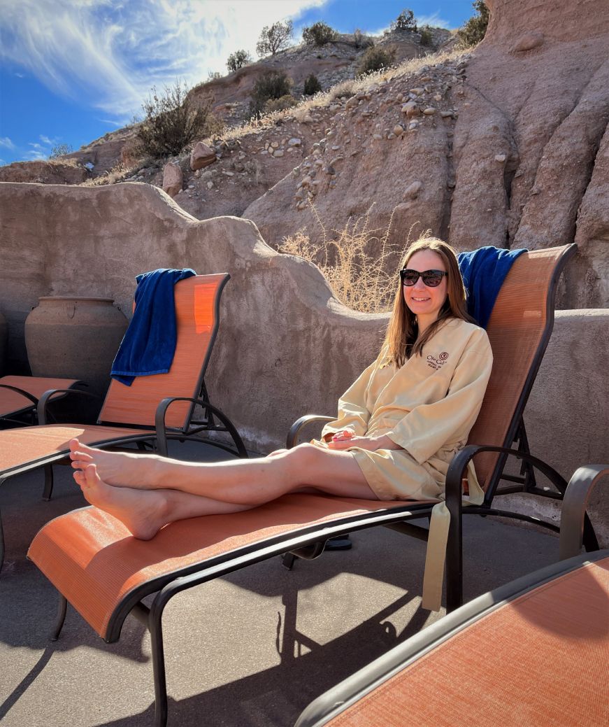 Stacy wearing a robe and sitting on a lounge chair with a rocky landscape in the background