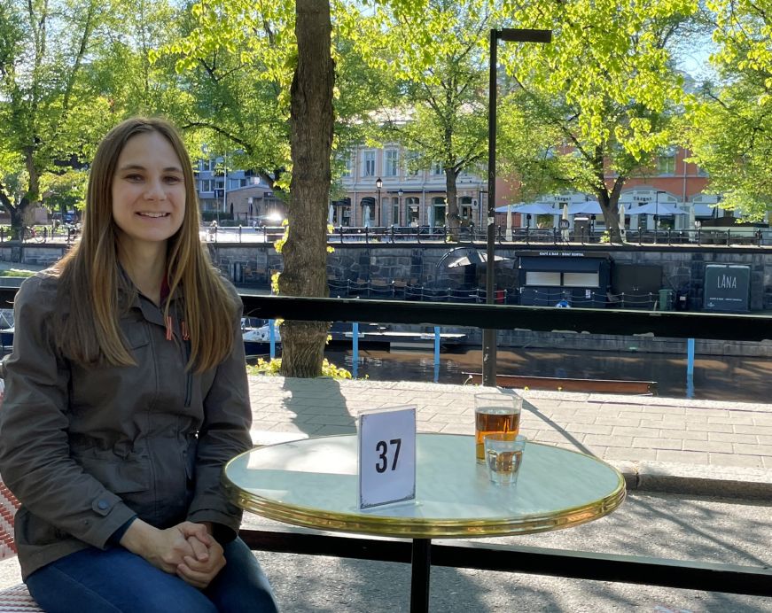 Stacy sitting at an outdoor restaurant table with a river in the background