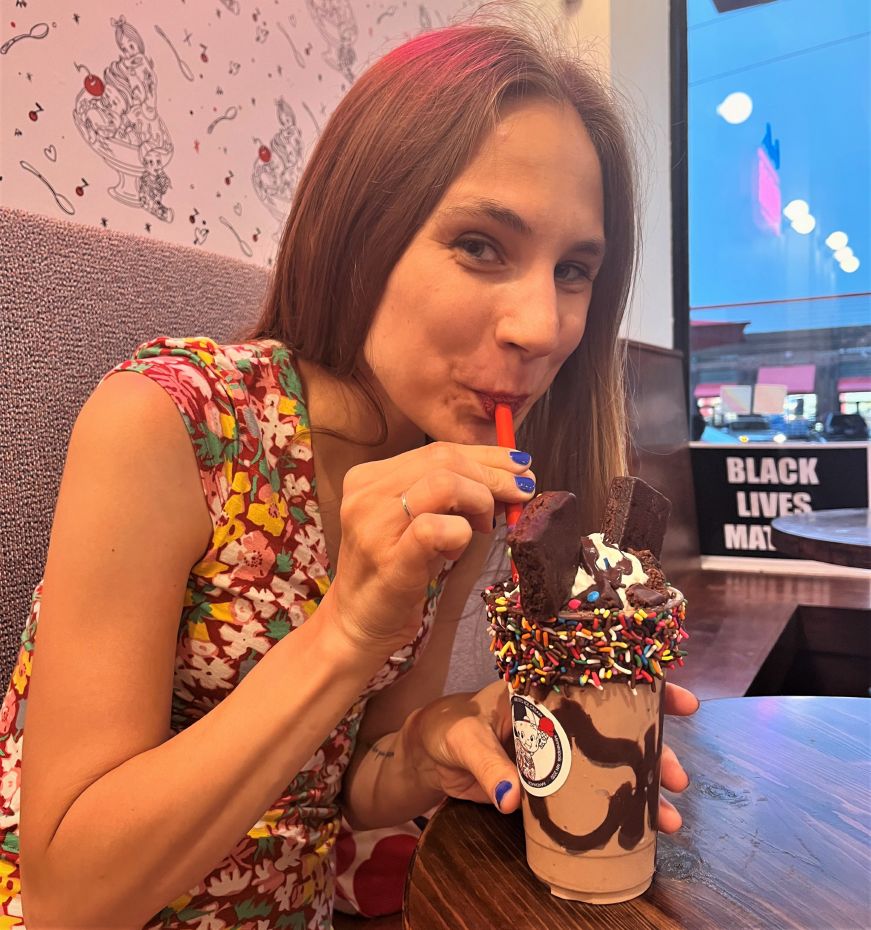 Stacy drinking Bebe Zito Cosmic Brownie Shake Stacy drinking chocolate shake garnished with brownies and sprinkles