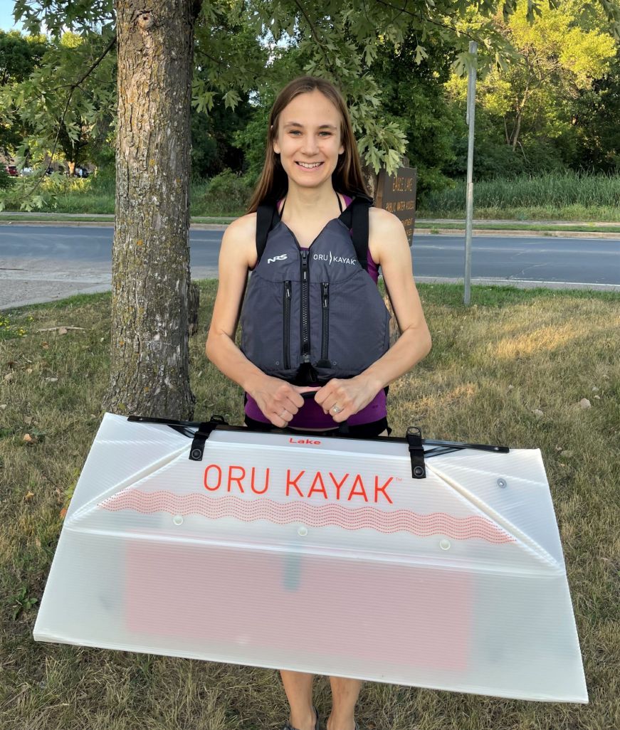 Stacy holding a folded up Oru Lake Kayak