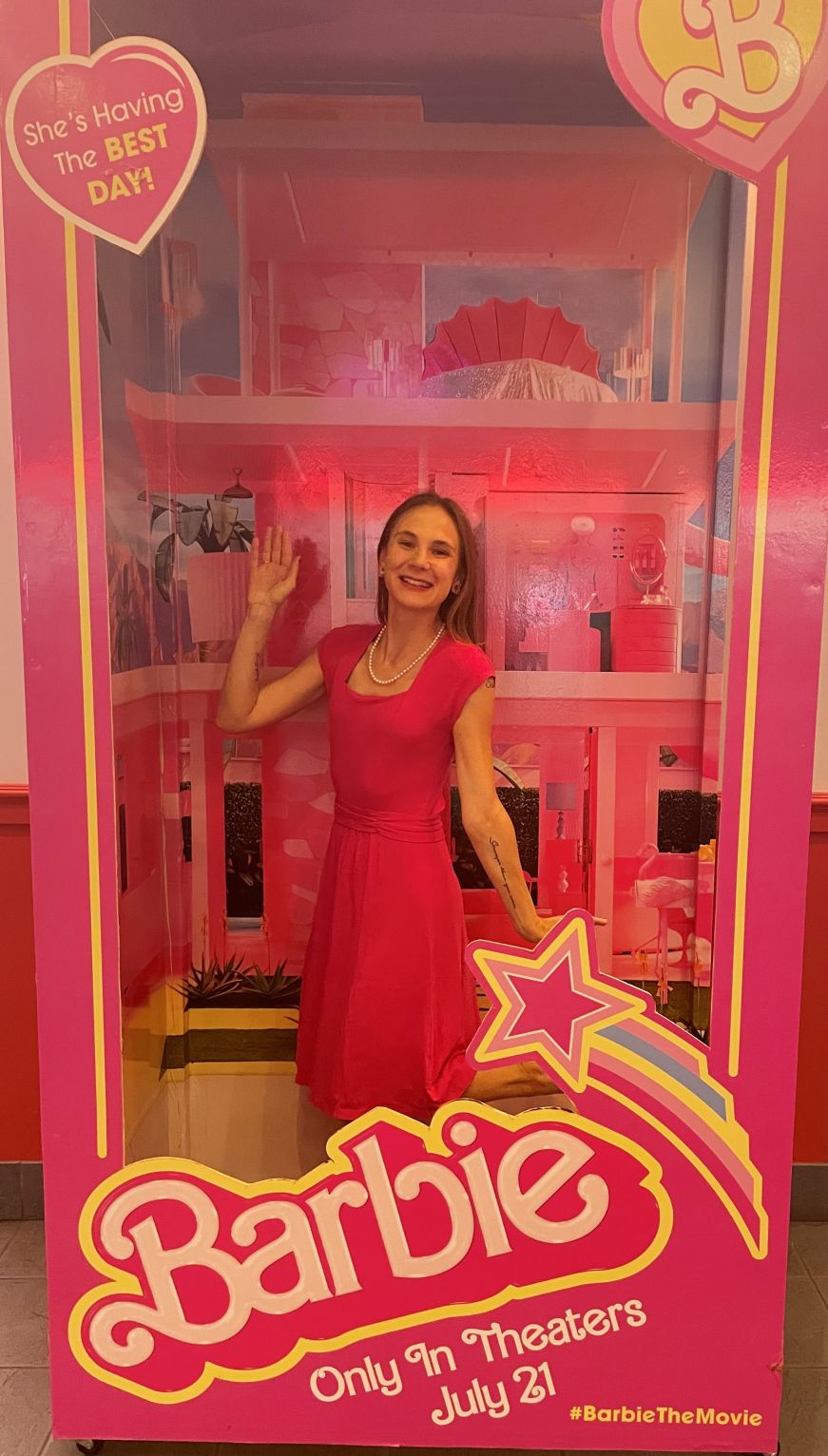 Stacy wearing a pink dress and posing in a life-size Barbie box