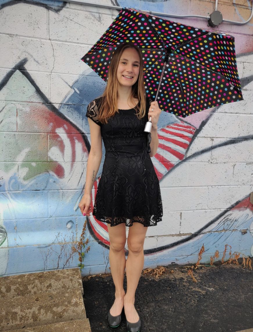 Stacy in a black lace mini dress holding a polka dot umbrella