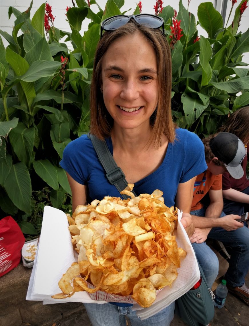 Stacy holding a cardboard dish heaped with potato chips