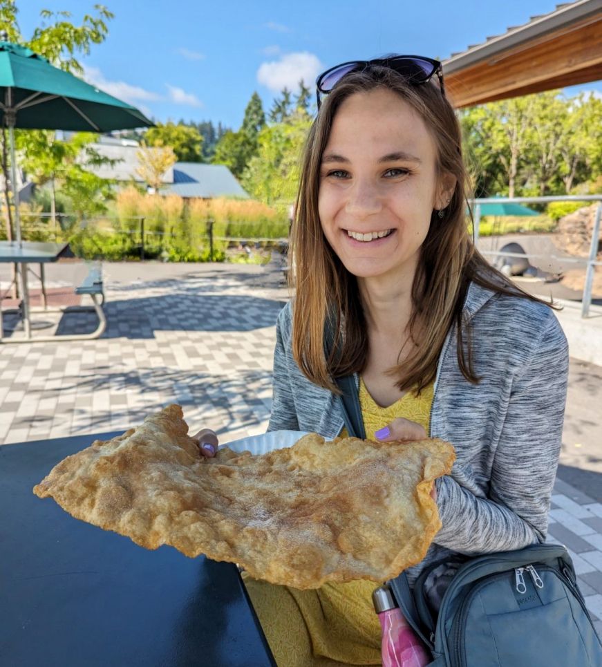 Stacy holding a large, flat pastry coated with cinnamon sugar