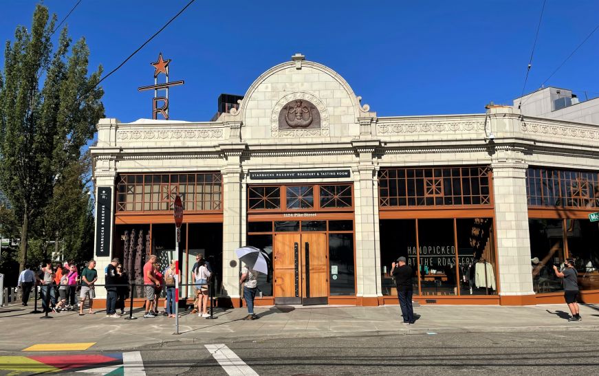 Ornate white building with line of people and sign reading Starbucks Reserve Roastery and Tasting Room