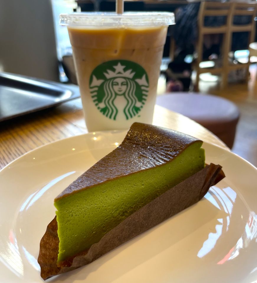 Sweet milk coffee and Uji matcha cheesecake, Starbucks Piece of matcha cheesecake with a Starbucks cup of iced coffee in the background