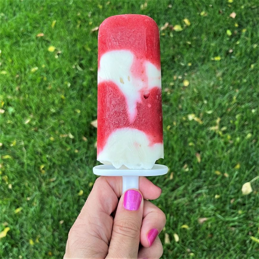 Homemade white and red swirled strawberries and cream popsicle 