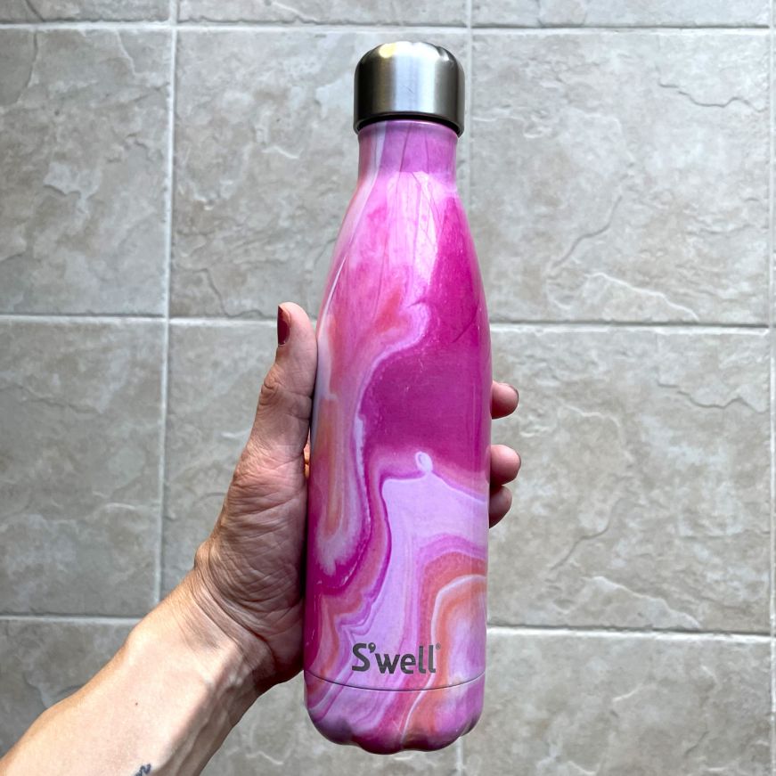 Stacy's hand holding a pink stainless steel water bottle