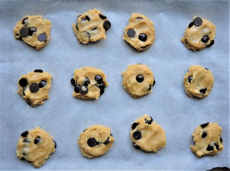 Unbaked tahini chocolate chip cookies on a parchment-lined baking sheeet