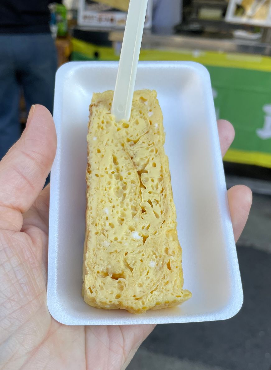 Hand holding a styrofoam plate with tamagoyaki