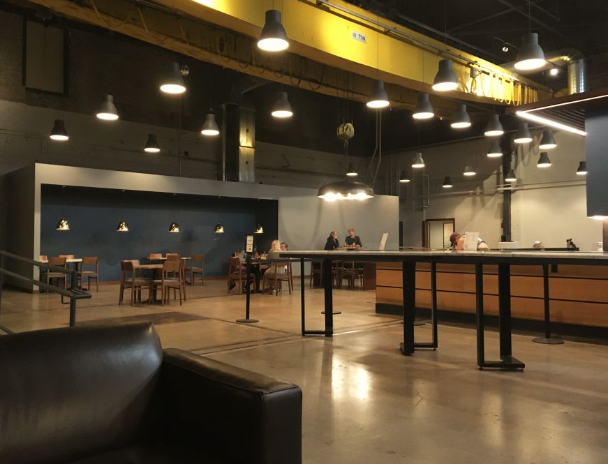 Interior of taproom with bar, tables, and pendant light fixtures