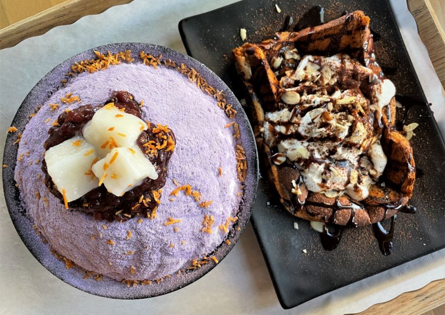 Bowl filled with shave ice topped with light purple taro powder and a plate with a piece of toast drizzled with chocolate