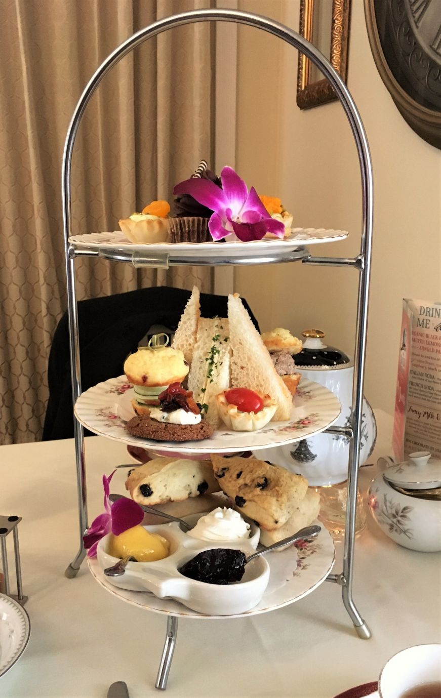 Three-tiered tea tower with scones, finger sandwiches, and miniature desserts