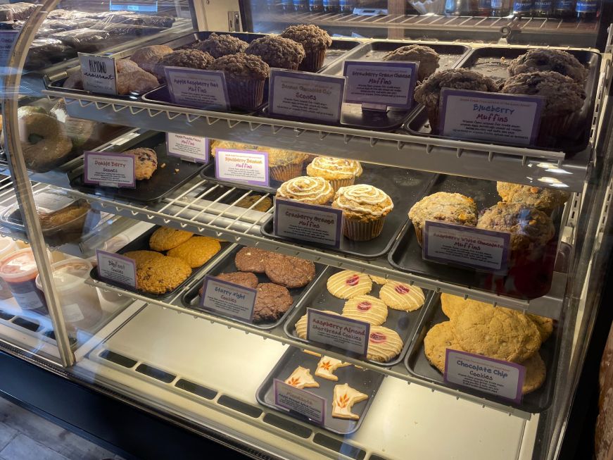 Bakery case stocked with large cookies, scones, and muffins