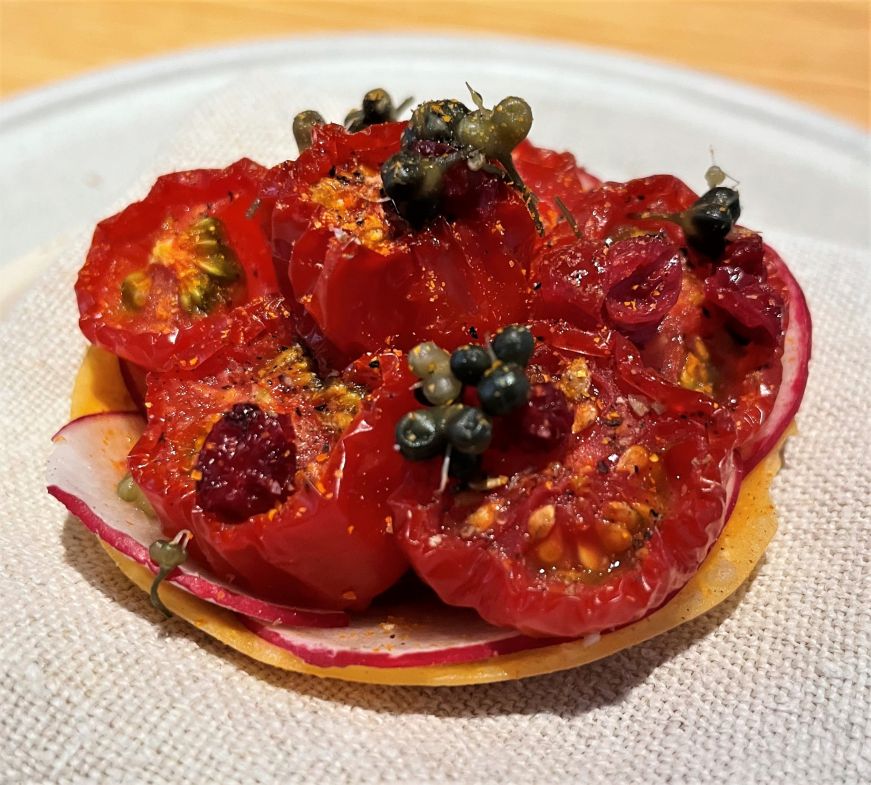 Small tart filled with cherry tomatoes and topped with capers