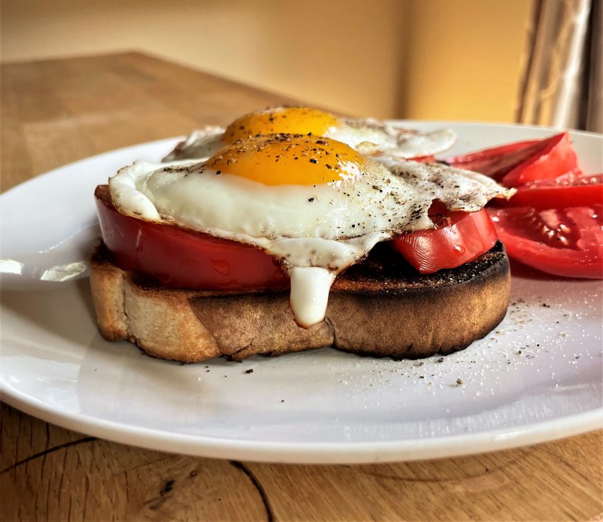 Slice of toast topped with sliced tomatoes and a fried egg