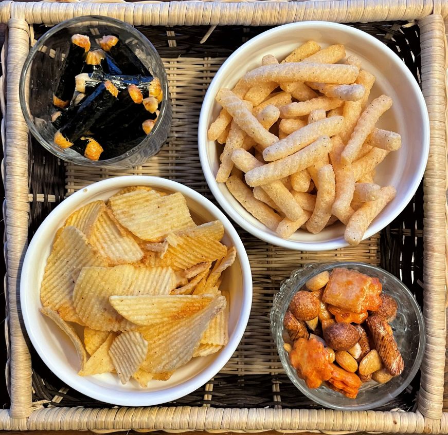Snacks from United Noodles Four bowls of chips and rice crackers on a wicker tray