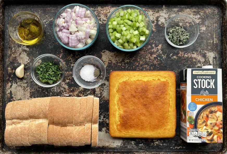 Top down view of a large baking sheet with two bread stuffing ingredients arranged on it