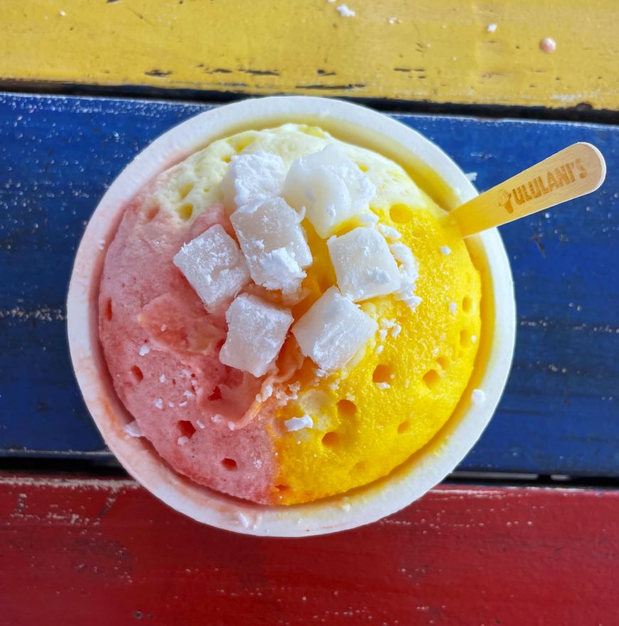 Top down view of a cup of shave ice topped with mochi and a snow cap