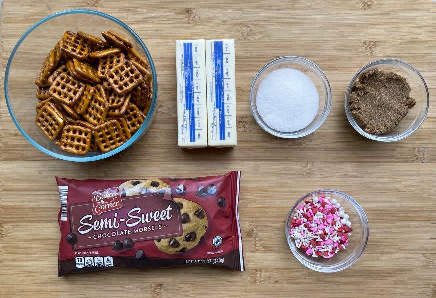 Valentine's pretzel bark ingredients arranged on a wood cutting board