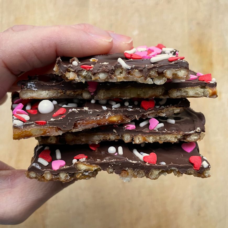 Hand holding a stack of Valentine's pretzel bark