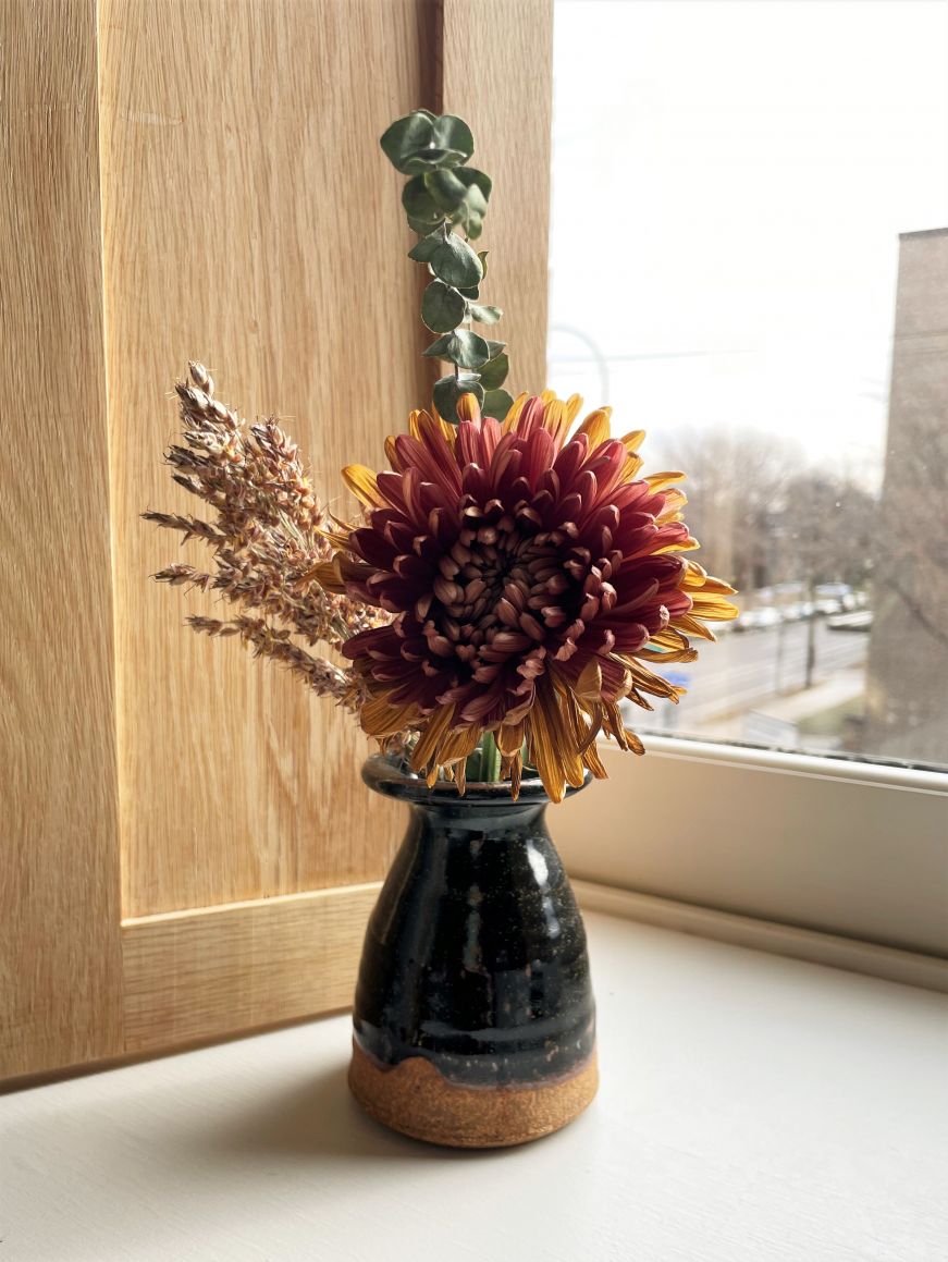 Fresh flower and greenery in a small ceramic vase