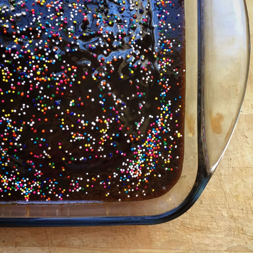 Chocolate cake with rainbow sprinkles in a glass baking dish