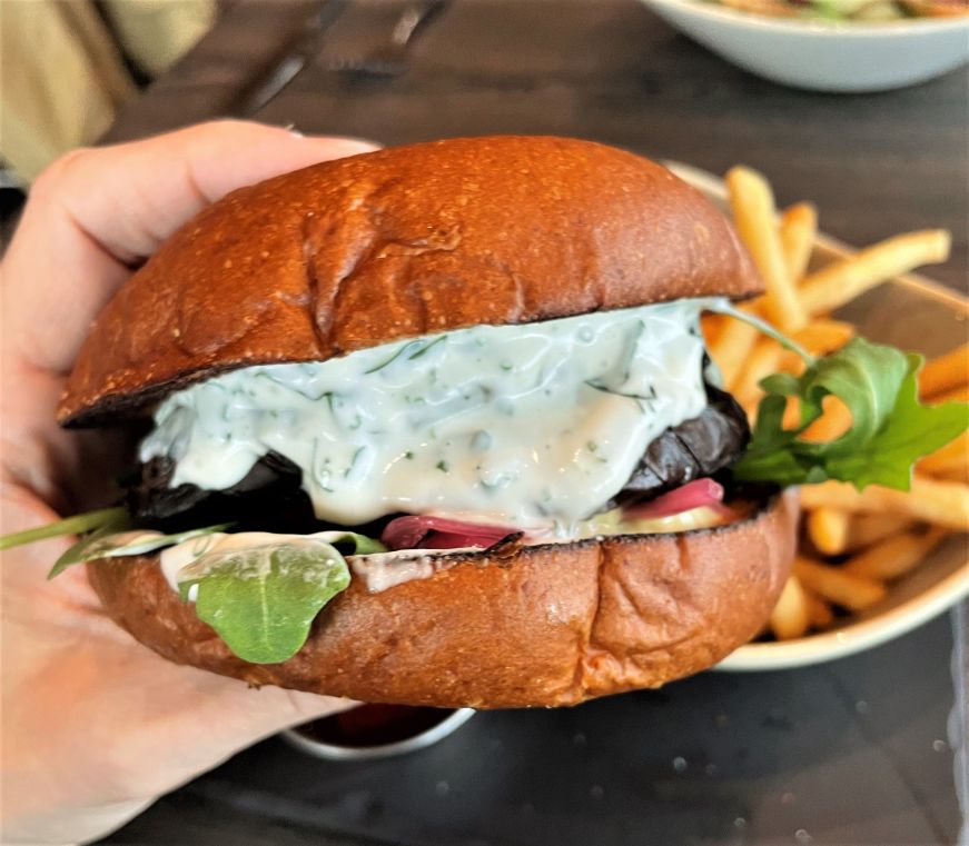 Vegetable burger, Sauna Restaurant Kuuma Hand holding a vegetable burger dripping with Green Goddess dressing