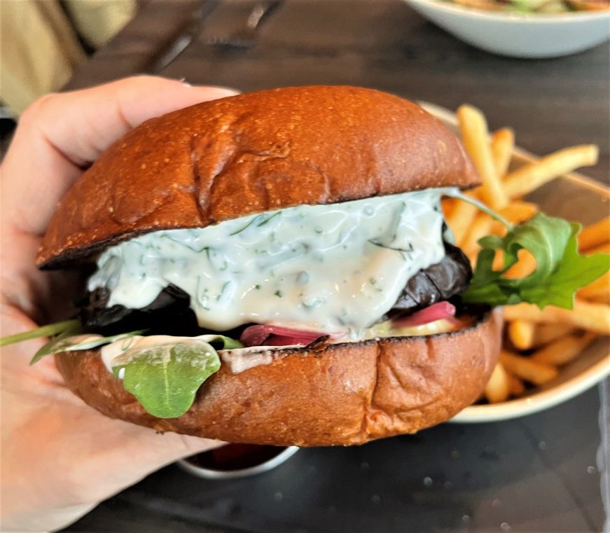 Hand holding a vegetable burger dripping with Green Goddess dressing